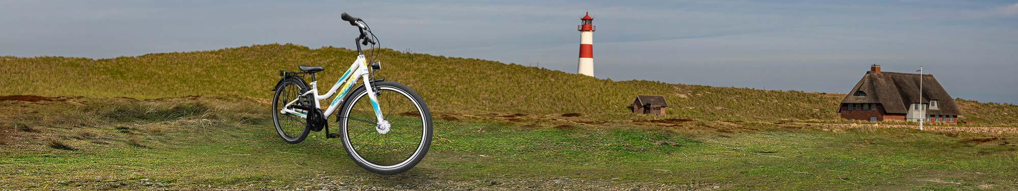 Kinderfahrrad vor Dünen mit Leuchtturm auf Sylt