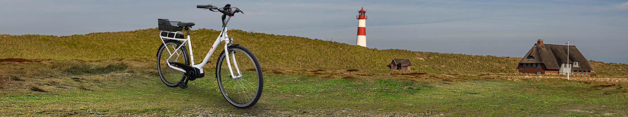 Elektrofahrrad vor Dünen mit Leuchtturm auf Sylt