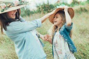 Mutter und Kind lachen mit Sommerhüten